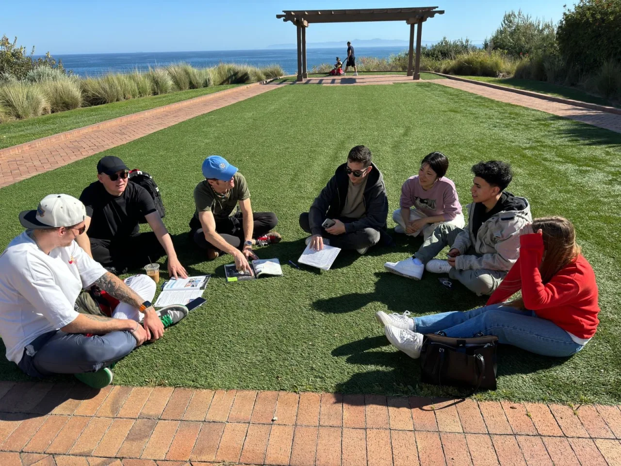 Students practicing English together outdoors by the coast